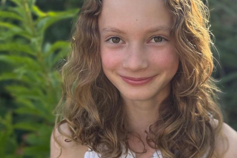 Aurelia standing in front of a tree with the sunlight behind her reflecting on her hair