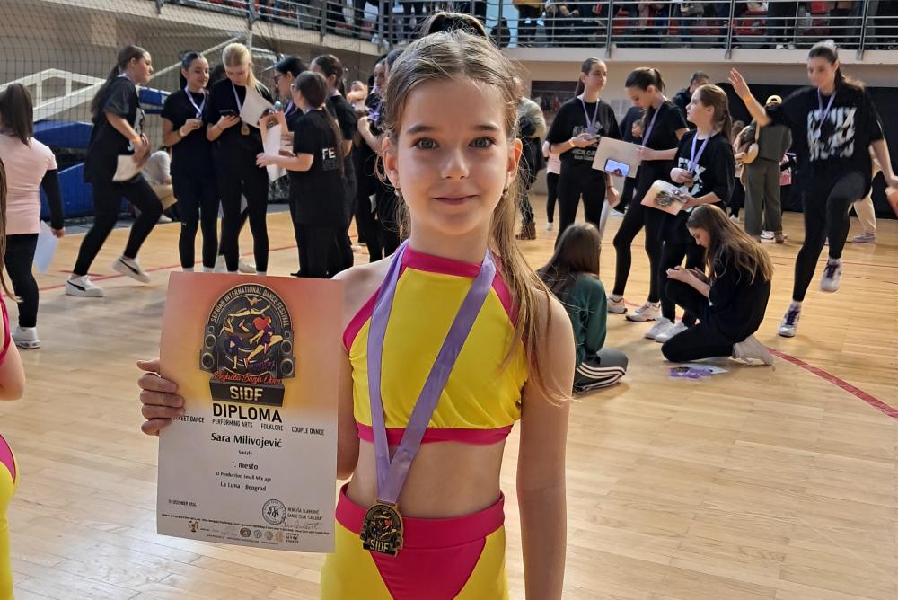 تظهر سارة وهي تحمل ميدالية فوزها بجائزة الرقص المعروف بال "بريك دانس" وهي تلبس فستاناً باللون الأصفر والأحمر