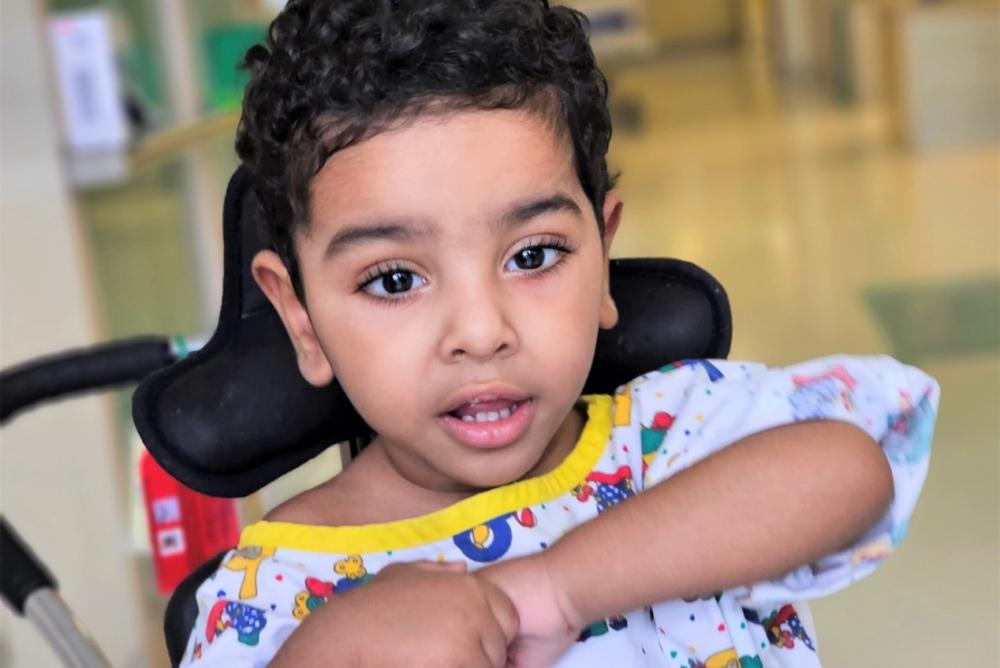 عز جالس على كرسي ويداه متشابكتان