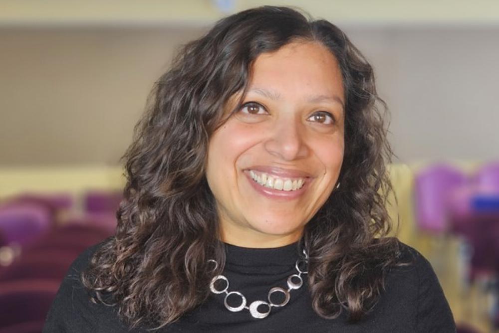 البروفيسورة كوريان تبتسم للكاميرا وخلفها كراسي في قاعة تدريب